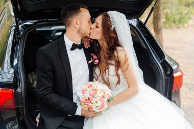 Güzel, lüks bir çiftin düğün yürüyüşü, gelin beyaz bir elbise ve bir buket ve damat açık havada siyah bir takım elbise içinde