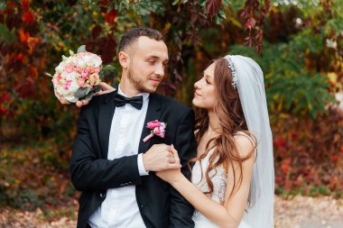 Güzel, lüks bir çiftin düğün yürüyüşü, gelin beyaz bir elbise ve bir buket ve damat açık havada siyah bir takım elbise içinde