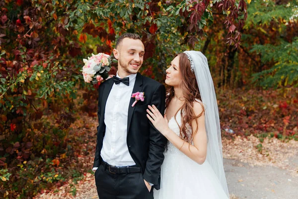 Wedding walk of a beautiful luxurious couple, the bride in a wedding white dress with a bouquet and the groom in a black suit in nature outdoors