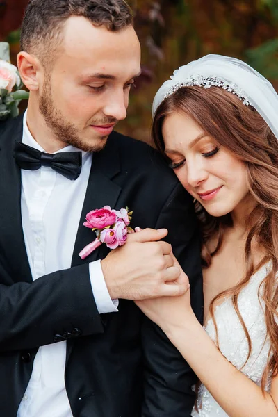 Wedding walk of a beautiful luxurious couple, the bride in a wedding white dress with a bouquet and the groom in a black suit in nature outdoors