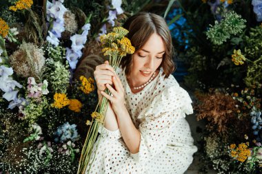 Güzel saç stili ve makyajlı, beyaz elbiseli, çiçekli, Vogue dergisi için moda tarzı bir odadaki kız model.