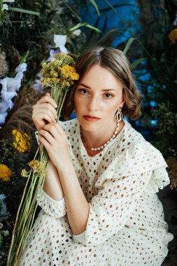 Güzel saç stili ve makyajlı, beyaz elbiseli, çiçekli, Vogue dergisi için moda tarzı bir odadaki kız model.