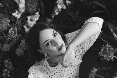 Güzel saç stili ve makyajlı, beyaz elbiseli, çiçekli, Vogue dergisi için moda tarzı bir odadaki kız model.