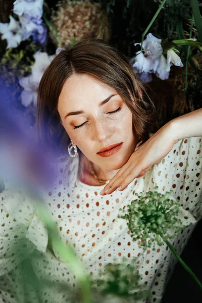 Güzel saç stili ve makyajlı, beyaz elbiseli, çiçekli, Vogue dergisi için moda tarzı bir odadaki kız model.