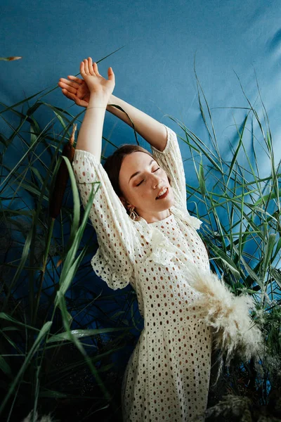 Güzel saç stili ve makyajlı, beyaz elbiseli, çiçekli, Vogue dergisi için moda tarzı bir odadaki kız model.