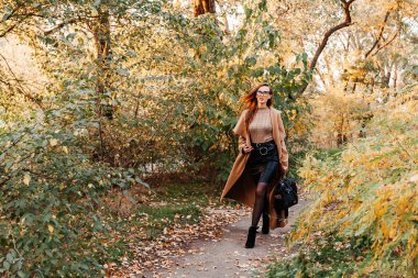 Paltolu güzel bir kız, siyah etek ve ceketli sonbahar yürüyüşleri şapkalı.