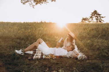 Beyazlı çift yazın günbatımında yeşil doğa üzerinde yürüyorlar.