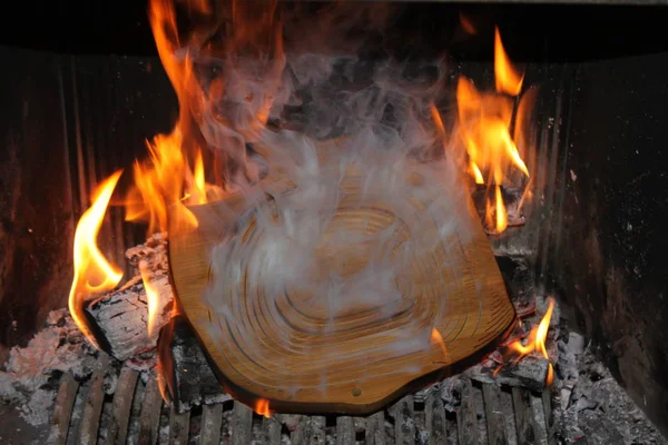 Wooden board in the oven with fire and smoke