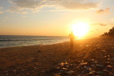  adam yürüyüş günbatımı plastik kirleticiler ile kıyı şeridi boyunca güneşe doğru