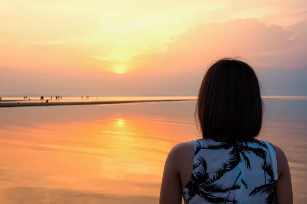 Young woman are standing watching the beautiful natural landscape, colorful of the sky and the sea during a sunset on the beach at Nathon Sunset Viewpoint in Ko Samui island, Surat Thani, Thailand