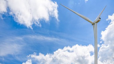 Mavi gökyüzünde güzel bir rüzgar türbini ve arka planda beyaz bulutlar, çevre dostu elektrik kaynağı küresel ısınmanın azalmasına yardımcı oluyor, 16: 9 geniş ekran