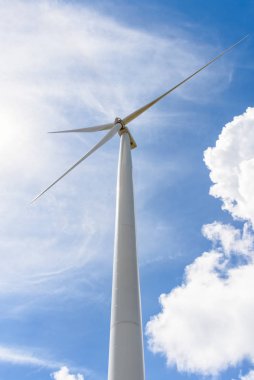 Mavi gökyüzünde güzel bir rüzgar türbini ve arka planda beyaz bulutlar, çevre dostu elektrik kaynağı küresel ısınmayı azaltmaya yardımcı olur
