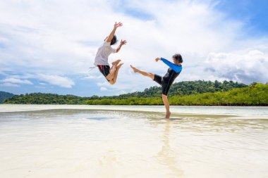 Çift plajda bir adam tekme eğlenceli kadın gösterisi oynamak