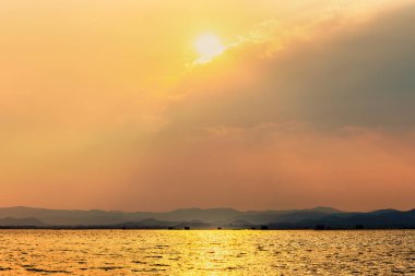 Güzel doğa manzarası bulutlarda parlak altın parıldıyor gökyüzüne sarı ışığı yansıtıyor ve su yüzeyi tropikal gölü Krasiao Barajı 'nda, Suphan Buri, Tayland