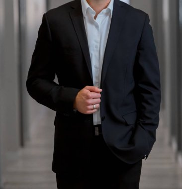 Elleri ceplerinde bir pasajda akıllı takım elbiseli kırpılmış kafa adam ayakta