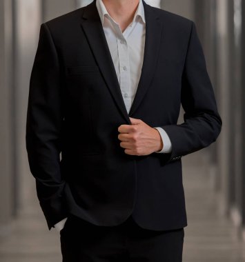 Elleri ceplerinde bir pasajda akıllı takım elbiseli kırpılmış kafa adam ayakta