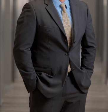 Elleri ceplerinde bir pasajda akıllı takım elbiseli kırpılmış kafa adam ayakta