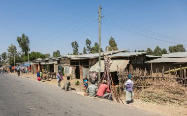 Addis Ababa, Etiyopya, 30 Ocak 2014, arka planda bir kaç kayıt dışı mağazaları ile yoğun bir cadde üzerinde oturan kadın ve erkek