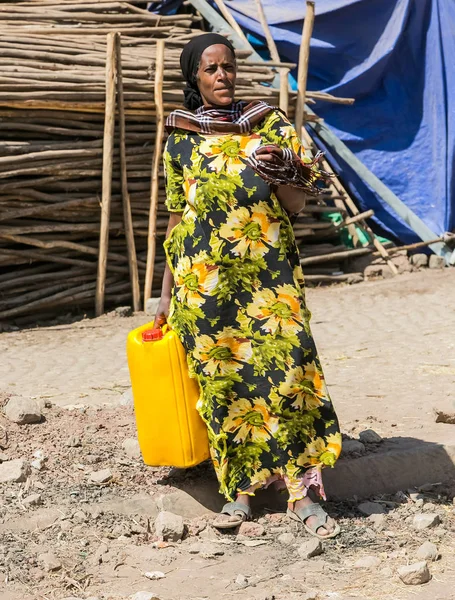 Doğruca kameraya bakarak sessiz bir toprak yol üzerinde bir su varil tutan Addis Ababa, Etiyopya, 30 Ocak 2014, Afrika kadın