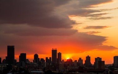 Kentsel alanda dramatik bulutlu gökyüzü gün batımında. Güneş'ten siluet binalar ve lens flare