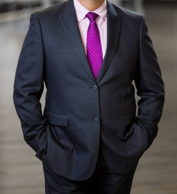 Elleri ceplerinde bir ofiste olan akıllı takım elbiseli kırpılmış kafa adam ayakta