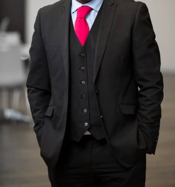 Elleri ceplerinde bir ofiste olan akıllı takım elbiseli kırpılmış kafa adam ayakta