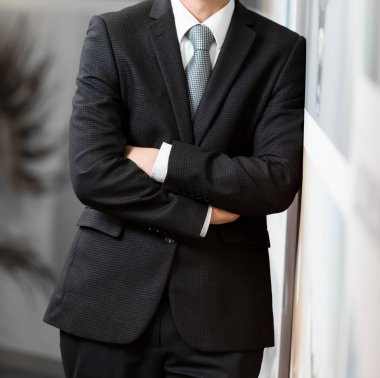 Akıllı takım elbiseli kafa adam ayakta bir ofiste katlanmış silah ile kırpılmış