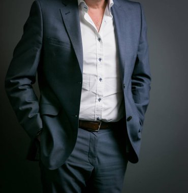 Elleri ceplerinde bir ofiste olan akıllı takım elbiseli kırpılmış kafa adam ayakta