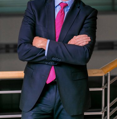 Akıllı takım elbiseli kafa adam ayakta bir ofiste katlanmış silah ile kırpılmış