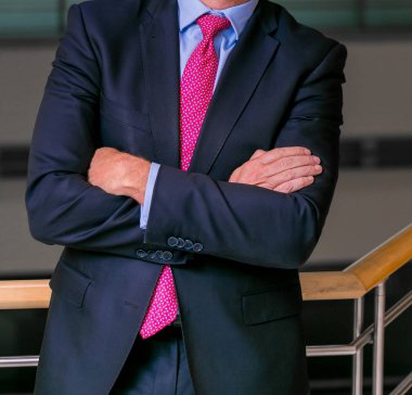 Akıllı takım elbiseli kafa adam ayakta bir ofiste katlanmış silah ile kırpılmış