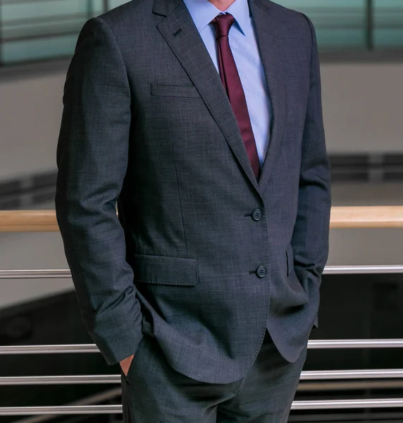 Elleri ceplerinde bir ofiste olan akıllı takım elbiseli kırpılmış kafa adam ayakta