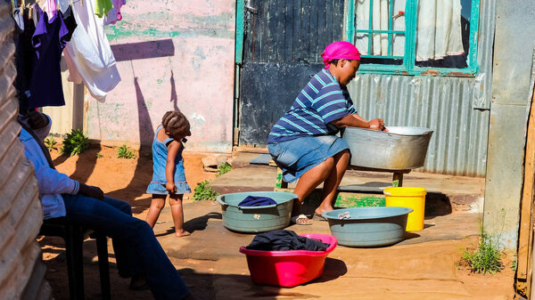 Осака, ЮАР, 11 сентября 2011 года, африканская мать и ребенок стирают одежду в районе Совето
 