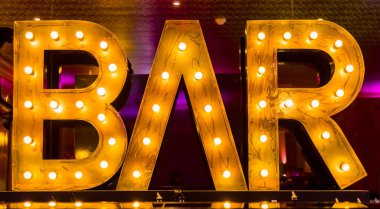 Arka plan aydınlatılmış bir Bar tabela olan bir Bar sayaç üzerinde kokteyl bardağı