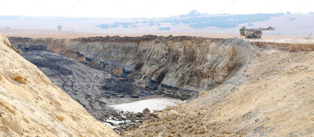 Open Pit coal mining with large equipment trucks for digging and transporting raw coal for processing
