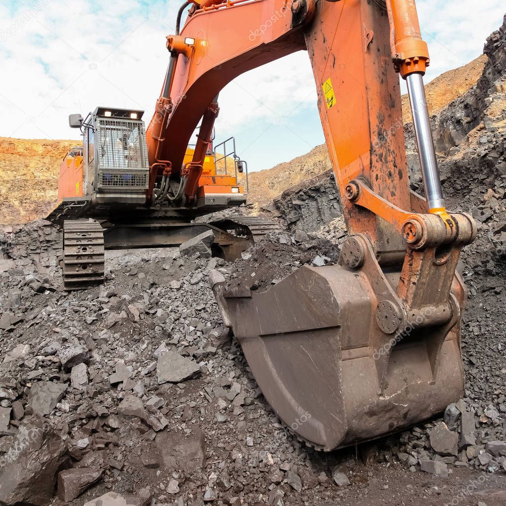 Excavator digging and loading ore rocks on a Manganese mine
