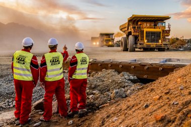 Rustenburg, Güney Afrika, 15 Ekim 2012, Platinum paladyum cevheri taşıyan Büyük Döküntü Kamyonları ön planda maden güvenlik denetçileriyle birlikte işlemek için