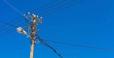 Telefon lamba direğine mavi gökyüzü karşı elektrik telleri ile