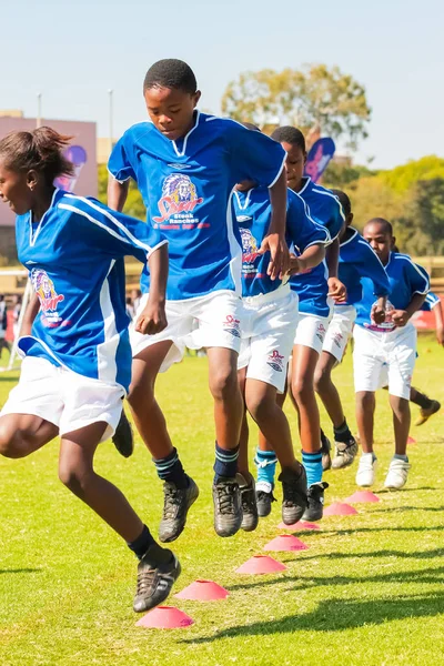 Разнообразные дети играют в футбол в школе — стоковое фото