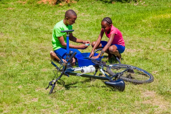 African Children fixing a puncture on a bike — Stock Photo, Image