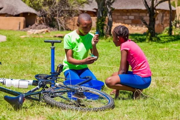 African Children fixing a puncture on a bike — Stock Photo, Image