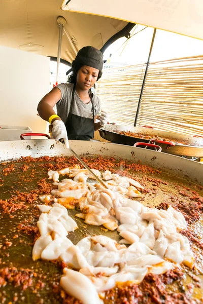Африканский женский шеф-повар готовит и подает паэлью на вынос — стоковое фото