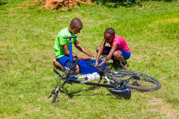 African Children fixing a puncture on a bike — Stock Photo, Image