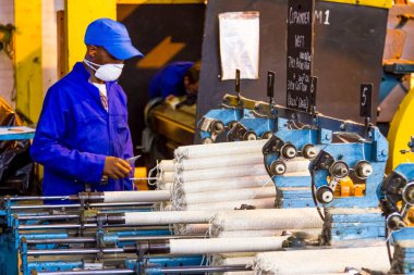 Johannesburg, Güney Afrika - 16 Ekim 2012: Copwinder Weft montaj hattı tezgahında çalışan Afrikalı fabrika işçisi