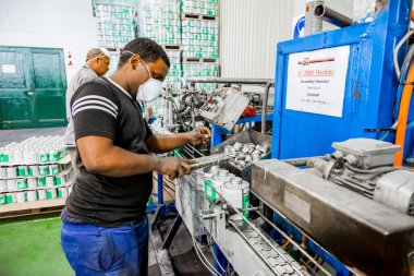 Johannesburg, Güney Afrika - 19 Ekim 2012: Yapıştırıcı fabrikasında üretim bandı üzerinde çalışan çeşitli insanlar