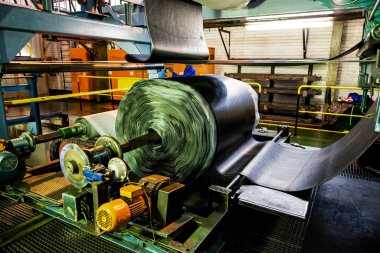 Johannesburg, Güney Afrika - 16 Ekim 2012: Afrikalı fabrika işçisi bir taşıma bandı fabrikasında lastik rulosunu kontrol ediyor