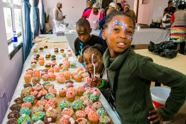 Johannesburg, South Africa - March 24, 2018: African children receiving cupcakes at Soup Kitchen volunteer community outreach program at orphanage  clipart