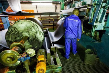 Johannesburg, Güney Afrika - 16 Ekim 2012: Afrikalı fabrika işçisi bir taşıma bandı fabrikasında lastik rulosunu kontrol ediyor