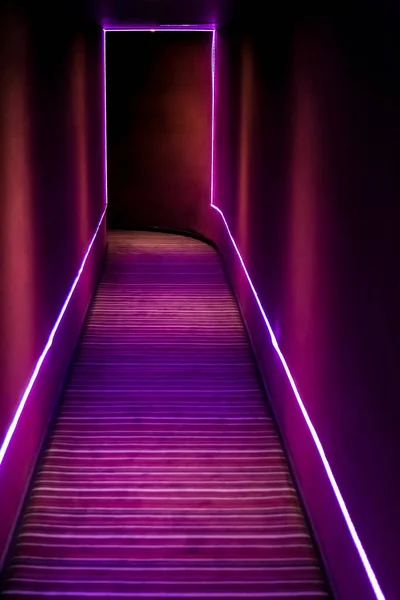 Dark passageway with purple neon strip lights at entrance to nightclub or theater