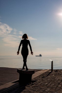 Genç güzel dans arkadan görünüm, Selanik, Yunanistan yerleştirme kutup kısa saçlı kadın uygun. Mavi deniz ve gökyüzü ve gemi içinde belgili tanımlık geçmiş arkadan görünüş