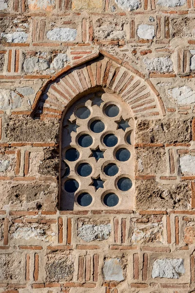 Ancient stone and ceramics arched window with Star of David and circles in a bright day